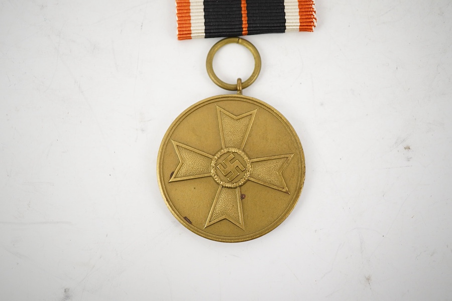 Nine German WWII medals; three Blood Order medals, a Second class Iron Cross, a War Merit medal in its original envelope, plus another unpacketed, a Second class War Merit cross, an Eastern Front Medal, and a West Wall M